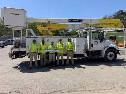 Five public power company workers in front of a work truck.